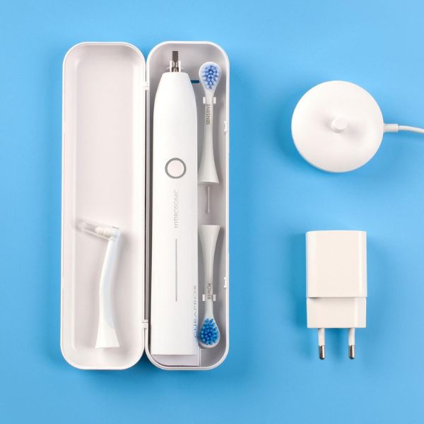 Curaprox Hydrosonic PRO zubná kefka a príslušenstvo Curaprox Hydrosonic PRO zubná kefka, biele púzdro, dve hlavice, adaptér, nabíjacia stanica a extra nadstavec na modrom podklade.