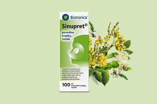 Krabička Bionorica Sinupret kvapiek s bylinkami v pozadí, položená na svetlozelenom povrchu.